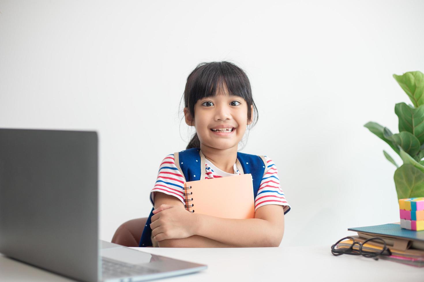 asiatisk studerande flicka bär skola ryggsäck och innehav övning bok. porträtt av Lycklig asiatisk ung tjej.tillbaka till skola foto