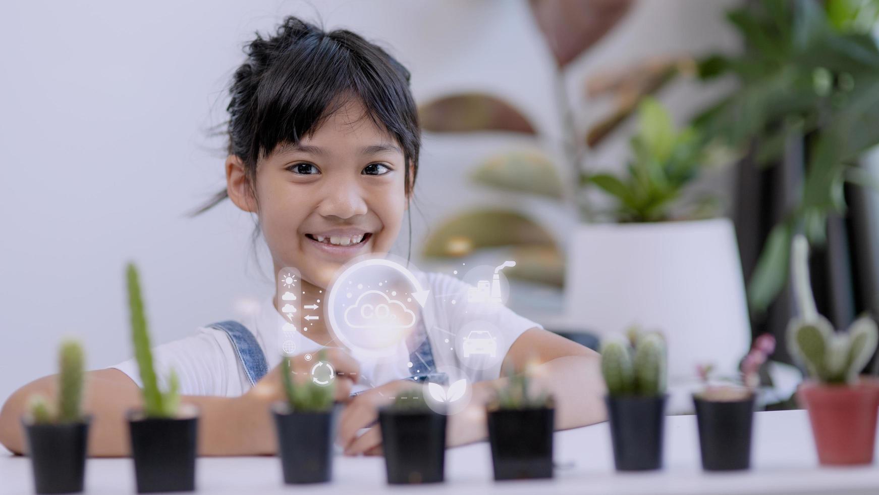 liten flicka tittar på en växt. miljö- teknologi begrepp. hållbar utveckling mål. sdgs. foto