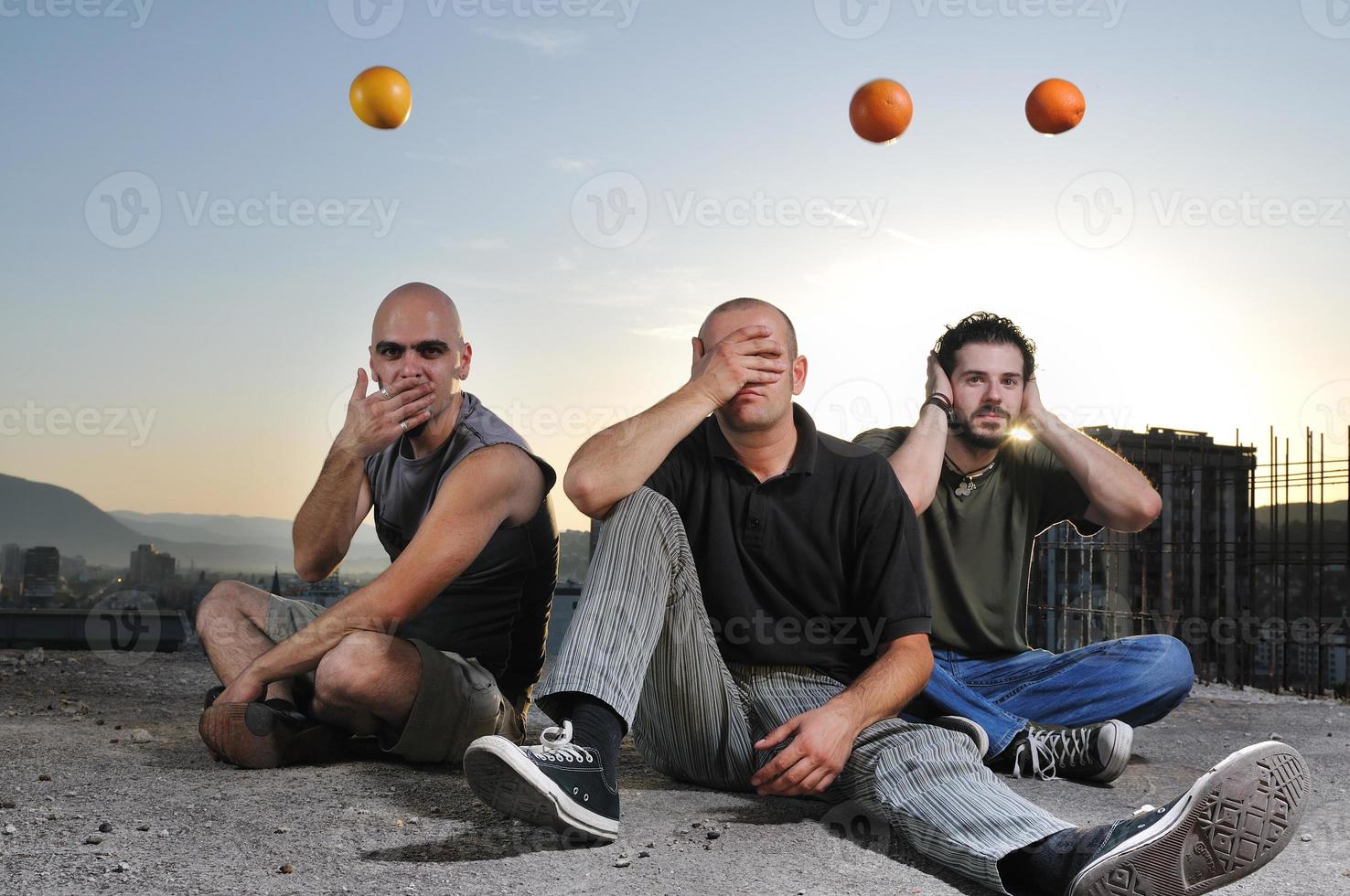 tre man utomhus- spela med orange frukt foto