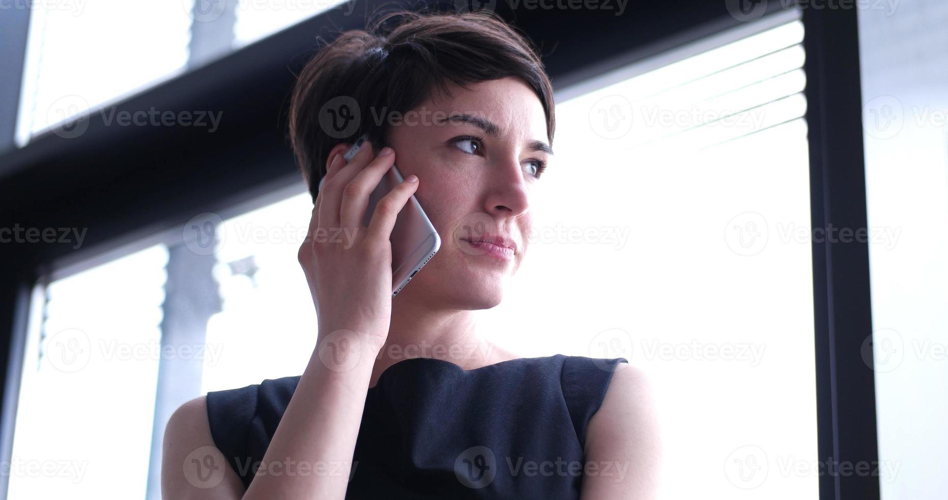 företag flicka stående i en modern byggnad nära de fönster med telefon foto