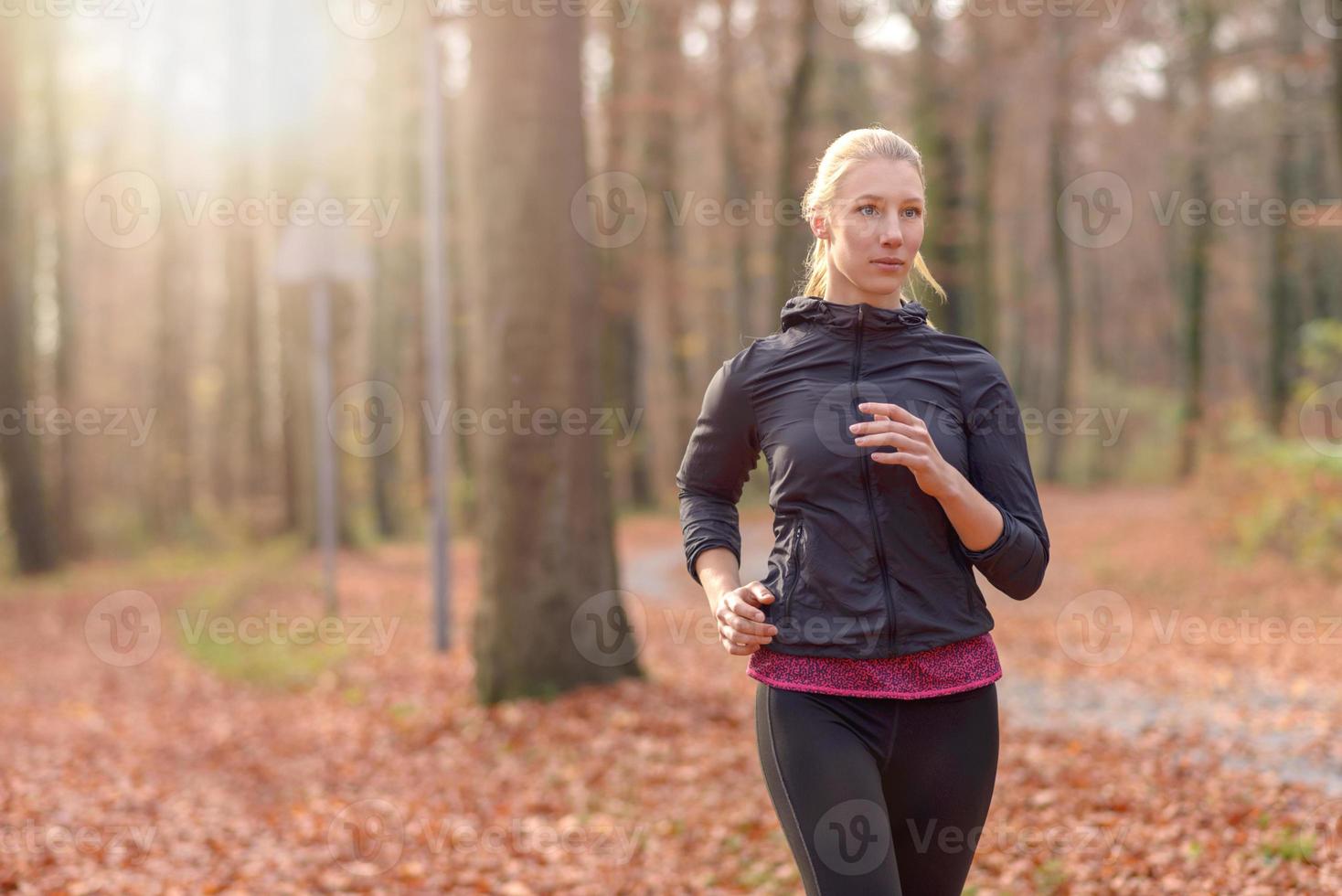 ganska passande ung kvinna som joggar i skogen foto