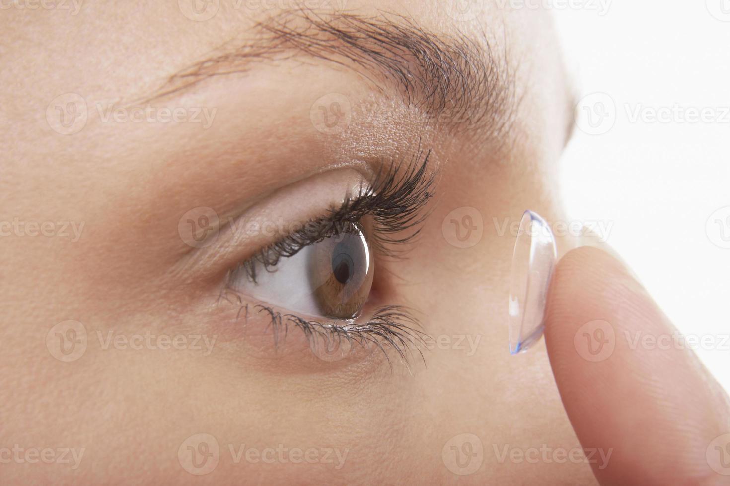 kvinna att sätta i kontaktlinsen foto