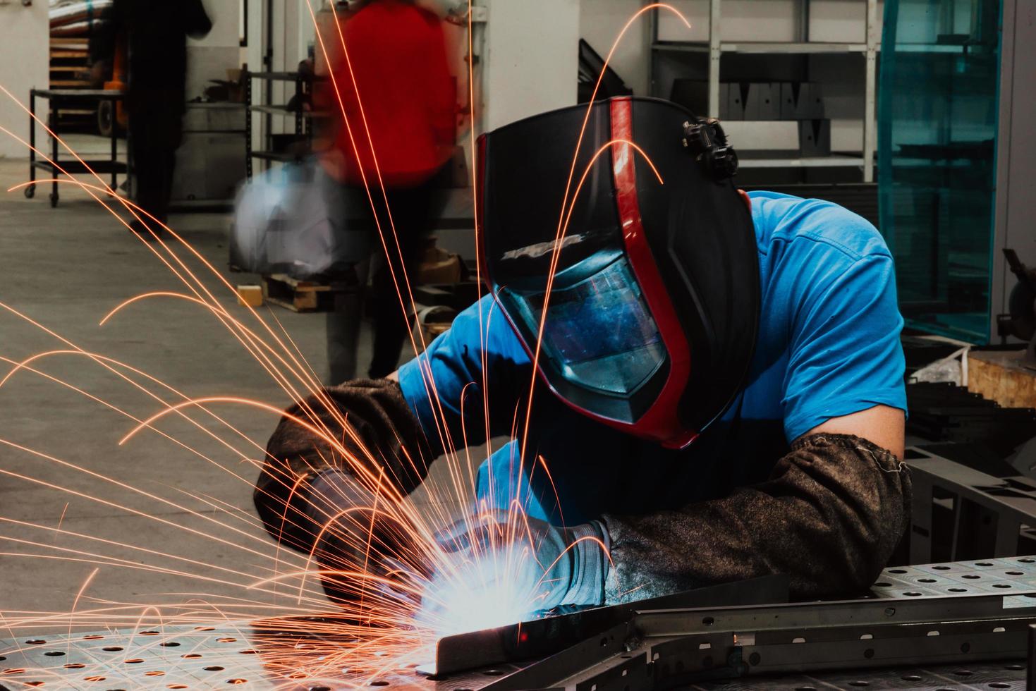 professionell tungindustrisvetsare som arbetar inne i fabriken, bär hjälm och börjar svetsa. selektiv fokusering foto