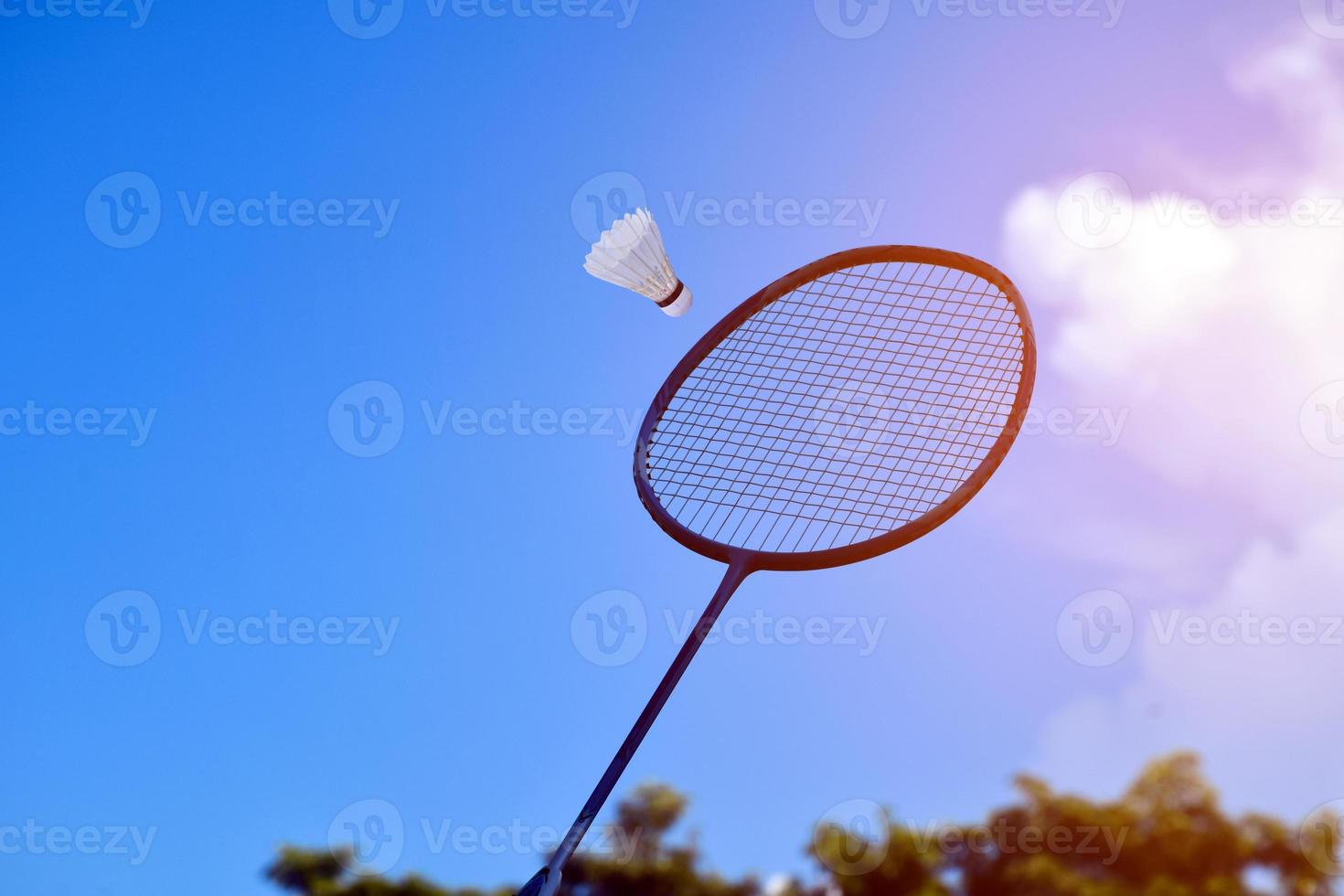 badminton racket och badminton fjäderboll mot molnig och blå himmel bakgrund, utomhus- badminton spelar begrepp. selektiv fokus på racket. foto