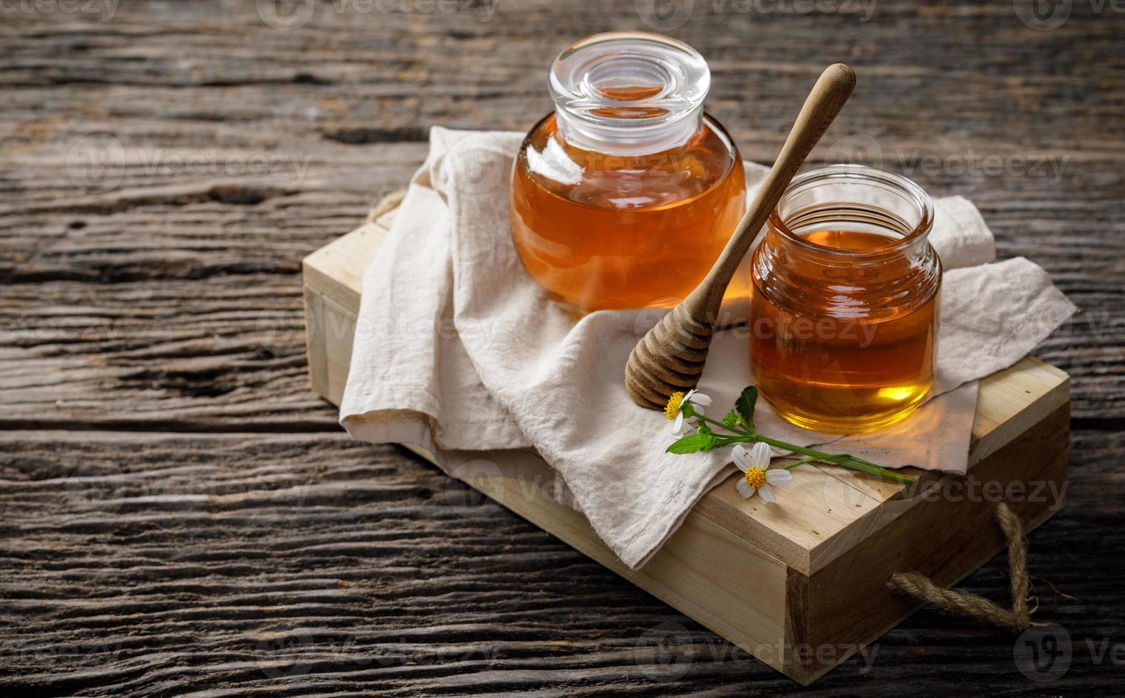 honung bi i burk med honung dipper och blomma på trä- tabell, bi Produkter förbi organisk naturlig Ingredienser begrepp, kopia Plats för din text foto