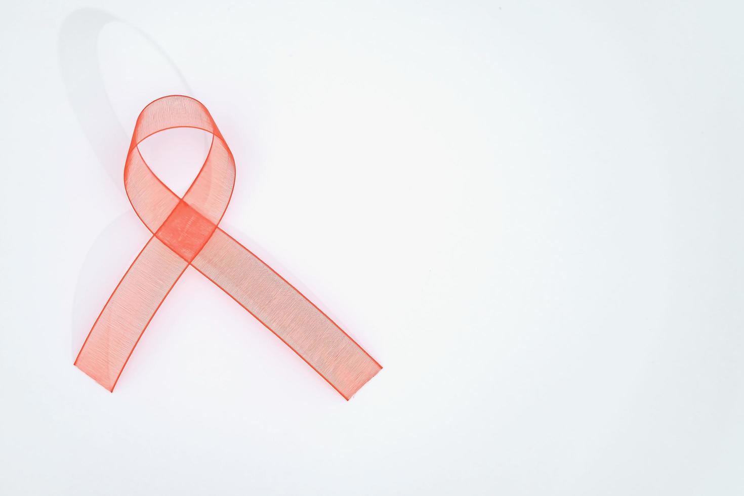 närbild röd band medvetenhet på vit bakgrund för värld AIDS dag kampanj. sjukvård och medicin begrepp. foto