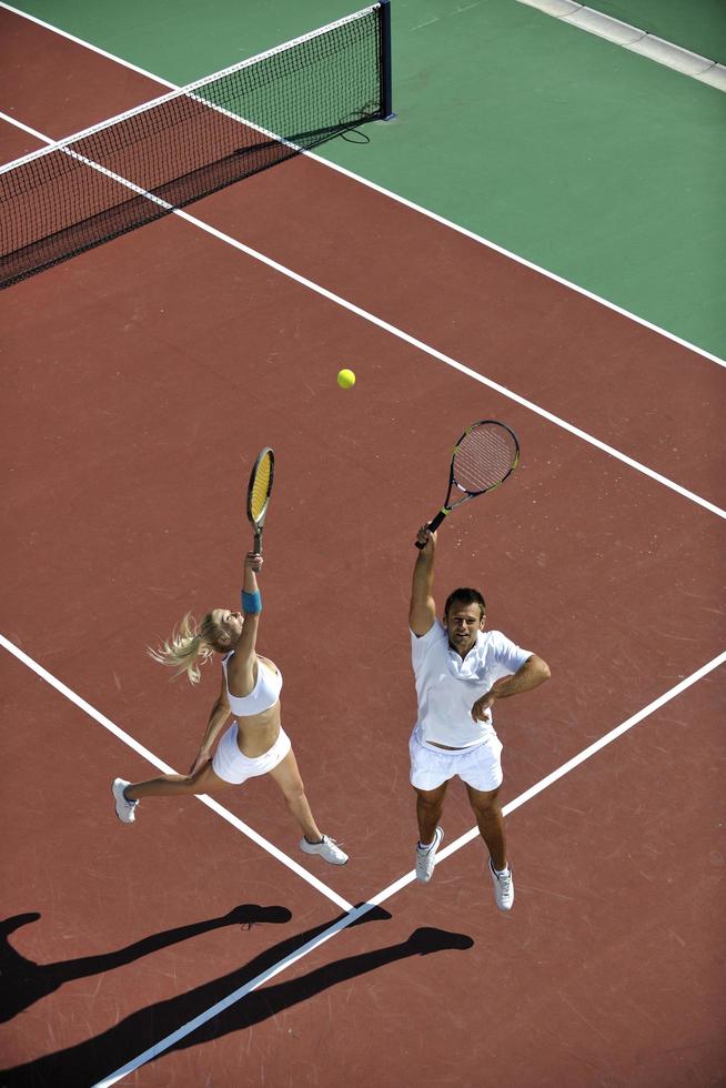 Lycklig ung par spela tennis spel utomhus- foto