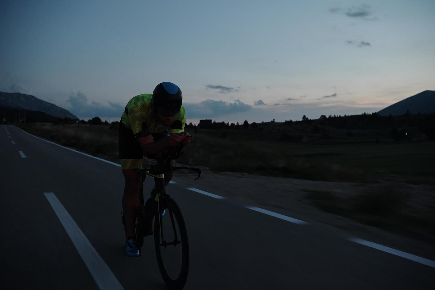 triathlon atlet cyklar på natten foto
