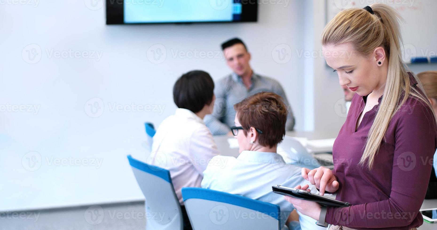 Söt affärskvinna använder sig av läsplatta i kontor byggnad under konferens foto