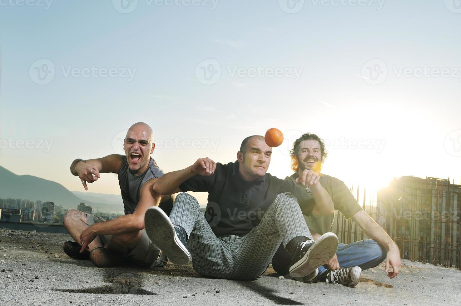 tre man utomhus- spela med orange frukt foto