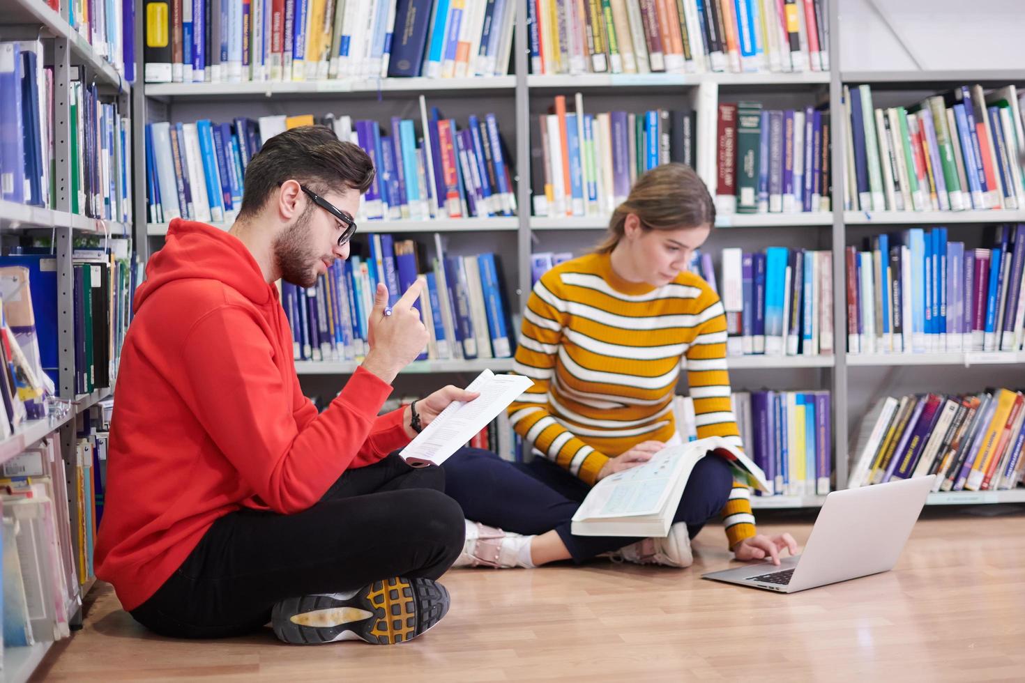 de studenter användningar en anteckningsbok, bärbar dator och en skola bibliotek foto