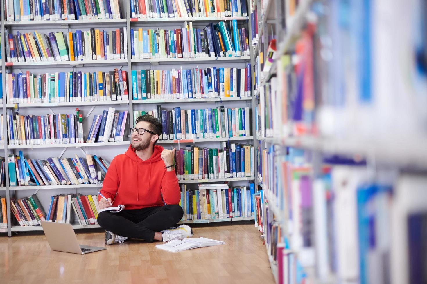 de studenter användningar en anteckningsbok, bärbar dator och en skola bibliotek foto