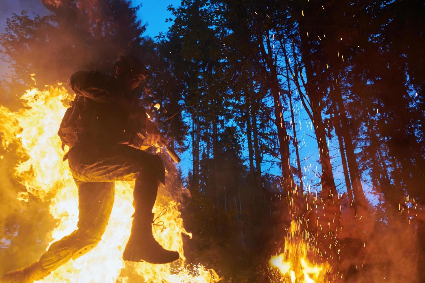 soldat i verkan på natt Hoppar över brand foto