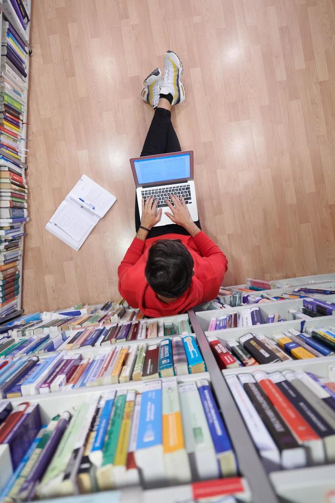 de studenter användningar en anteckningsbok, bärbar dator och en skola bibliotek foto