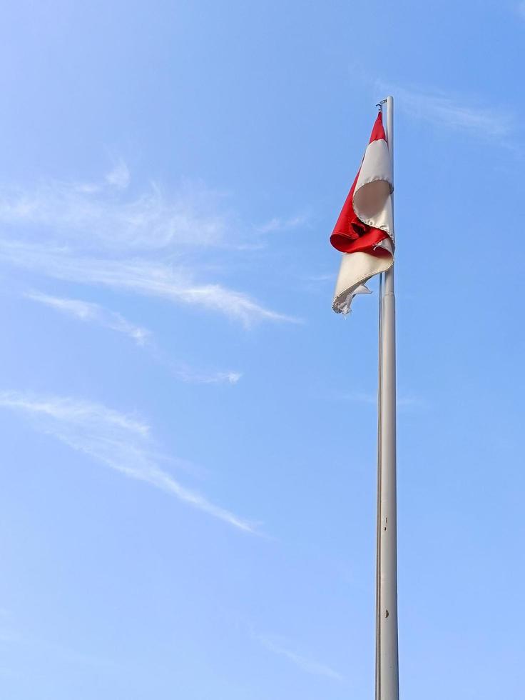 de röd och vit flagga fladdrar i de himmel mot de blå himmel bakgrund foto