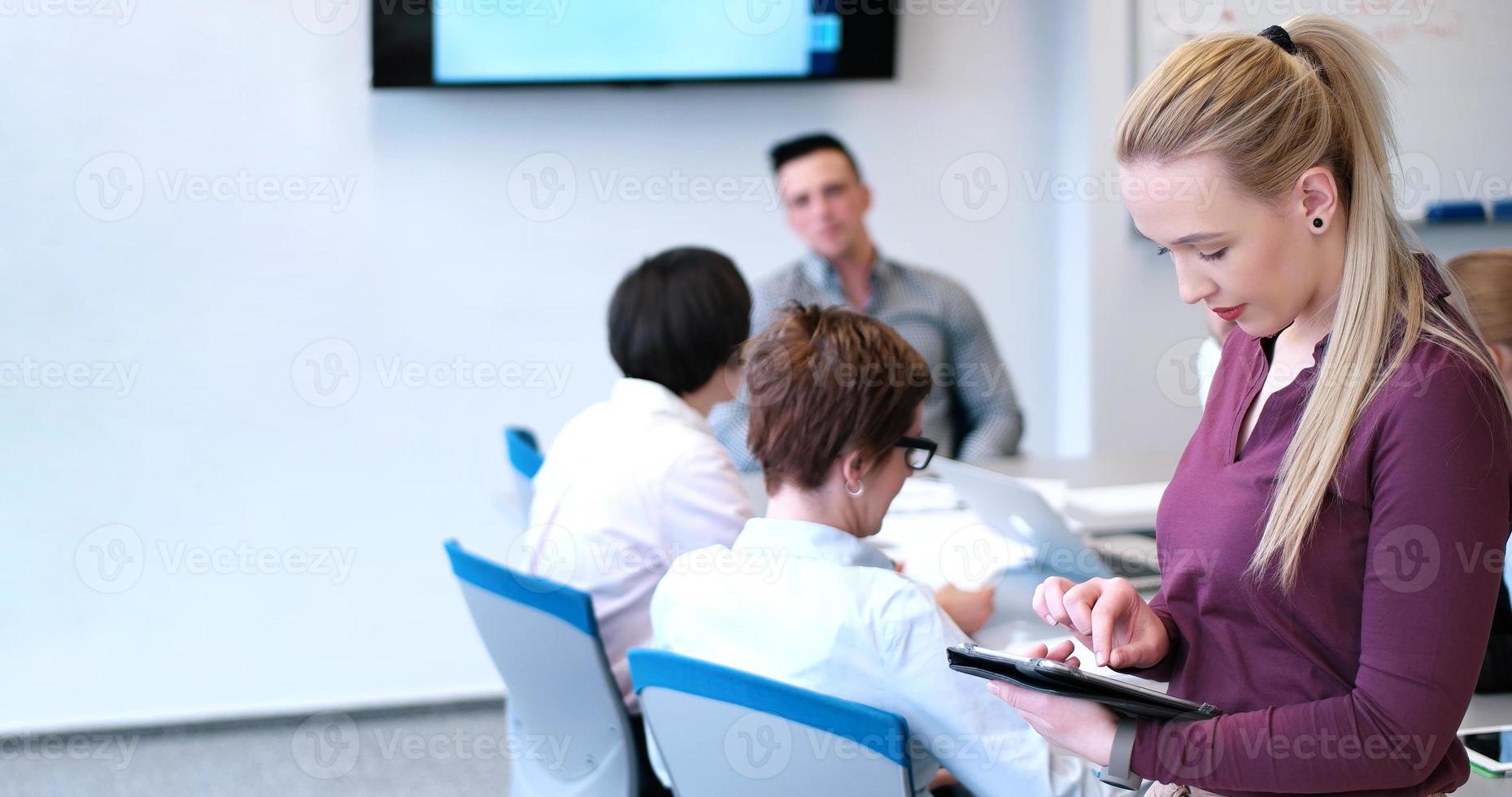 Söt affärskvinna använder sig av läsplatta i kontor byggnad under konferens foto