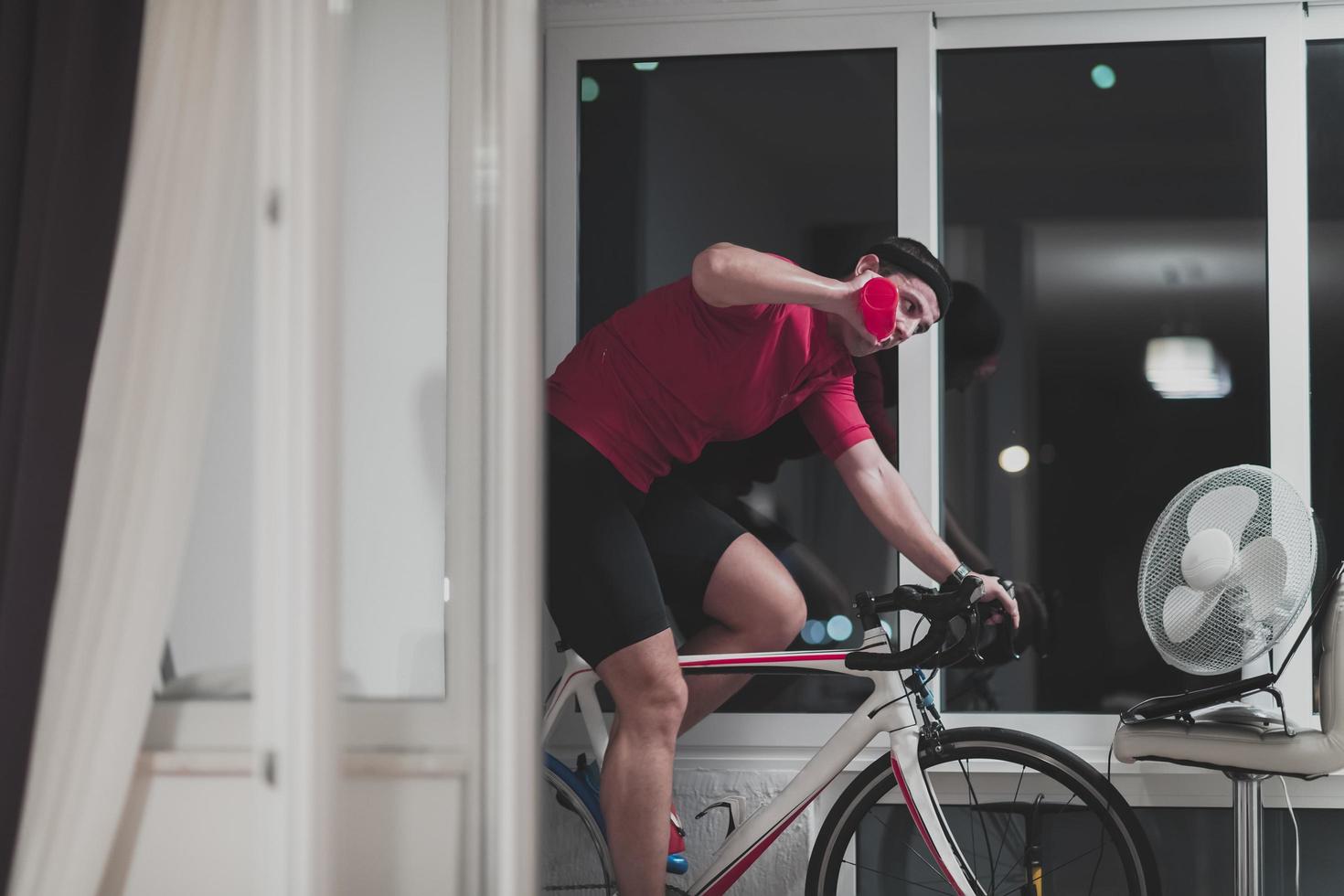 man cykling på de maskin tränare han är utövar i de Hem på natt spelar uppkopplad cykel tävlings spel foto