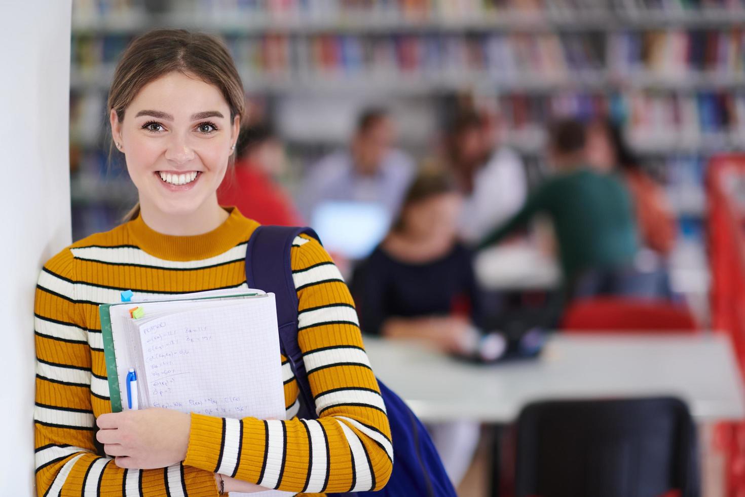 de studerande användningar en anteckningsbok och en skola bibliotek foto