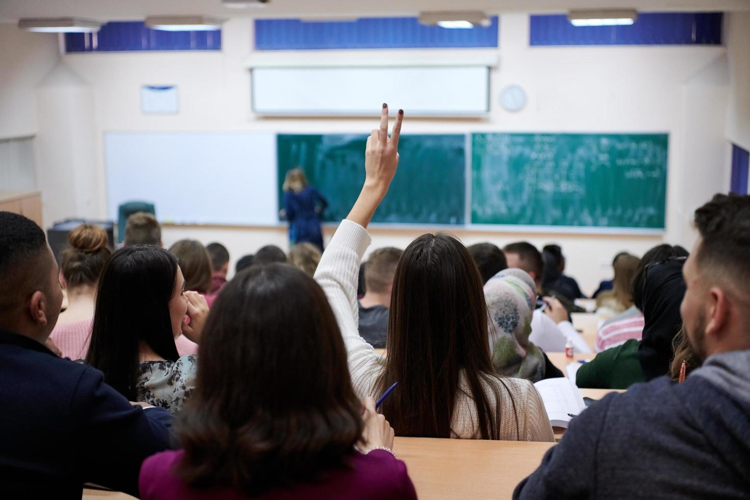 kvinna studerande Sammanträde i de klass och höjning hand upp foto