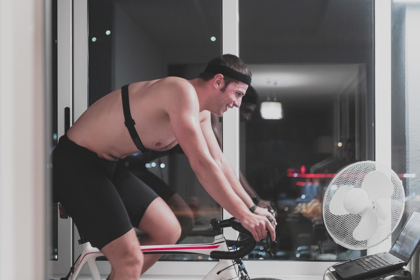 man cykling på de maskin tränare han är utövar i de Hem på natt spelar uppkopplad cykel tävlings spel foto