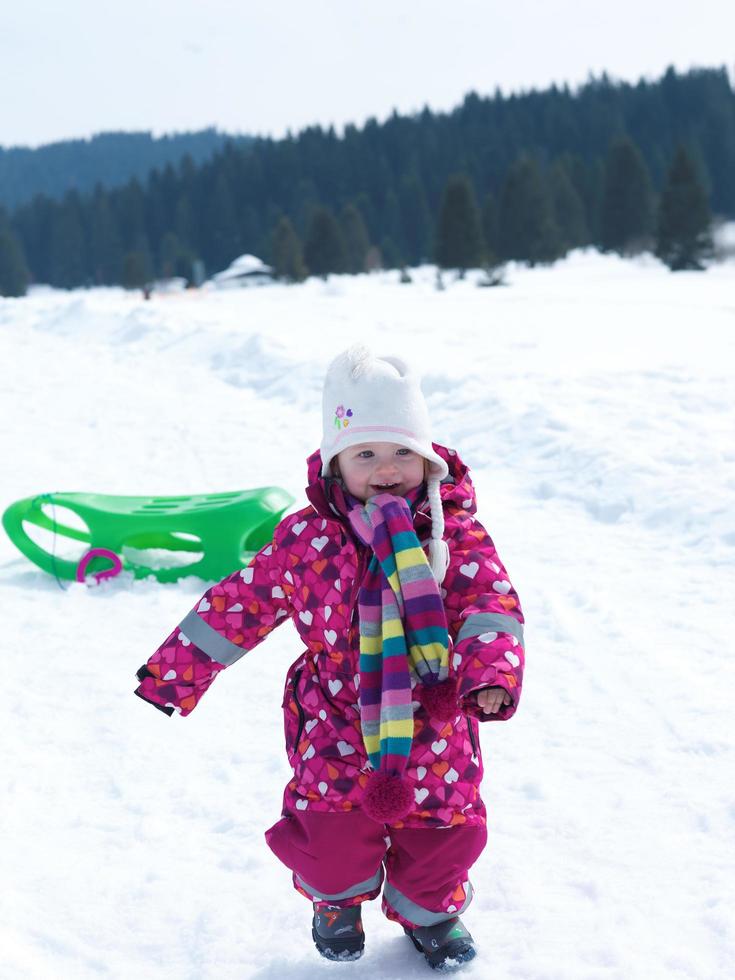 liten bebis flicka ha roligt på färsk snö foto