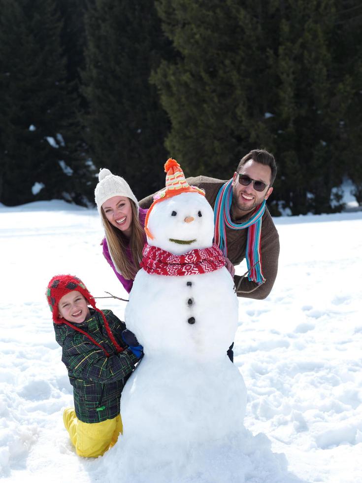 lycklig familj som gör snögubbe foto