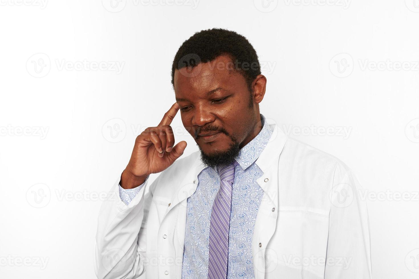 förvirrad svart läkare man med små skägg i vit morgonrock ljus skjorta isolerat på vit bakgrund foto