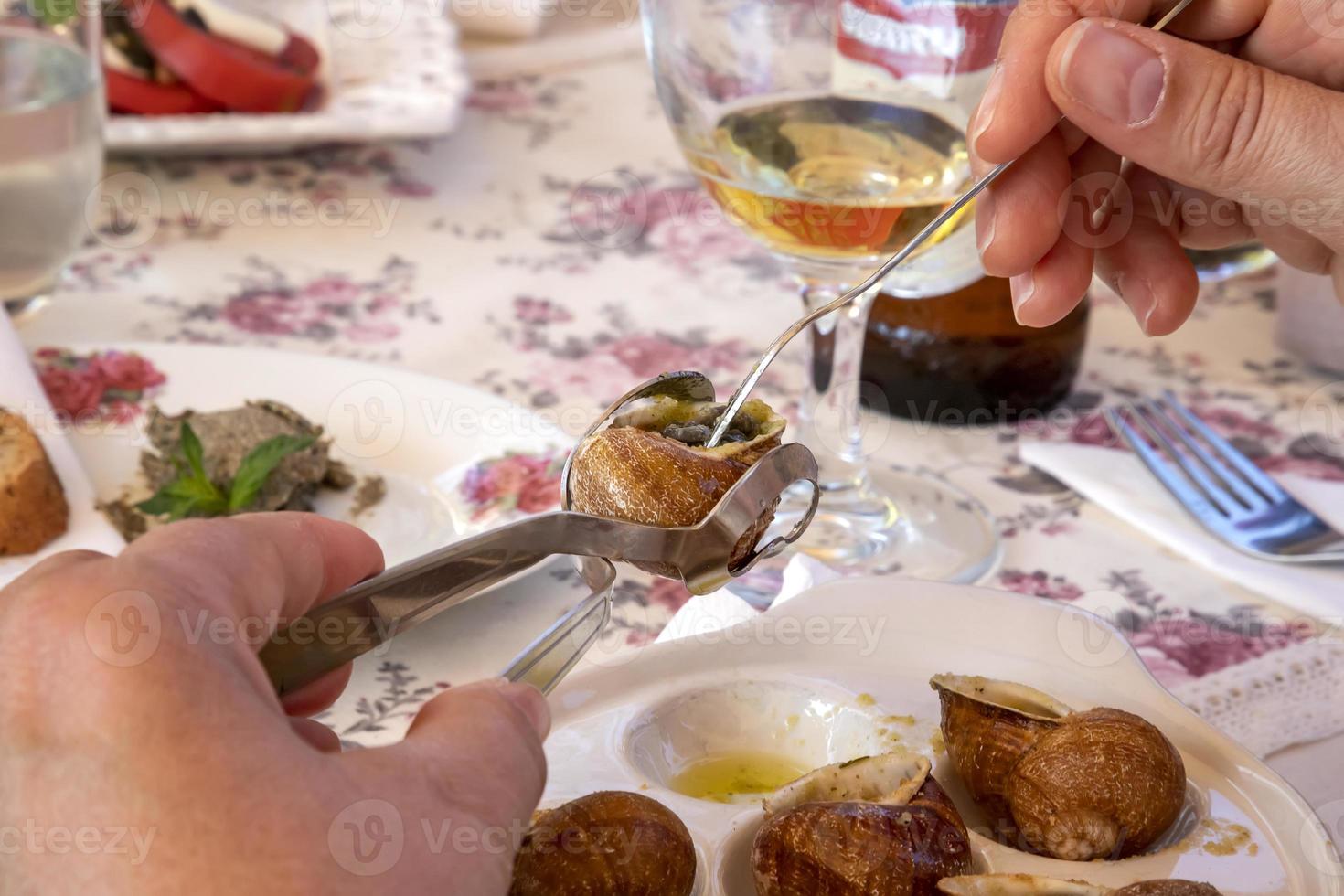 en kvinna äter utsökt escargots med citron- på de tabell foto