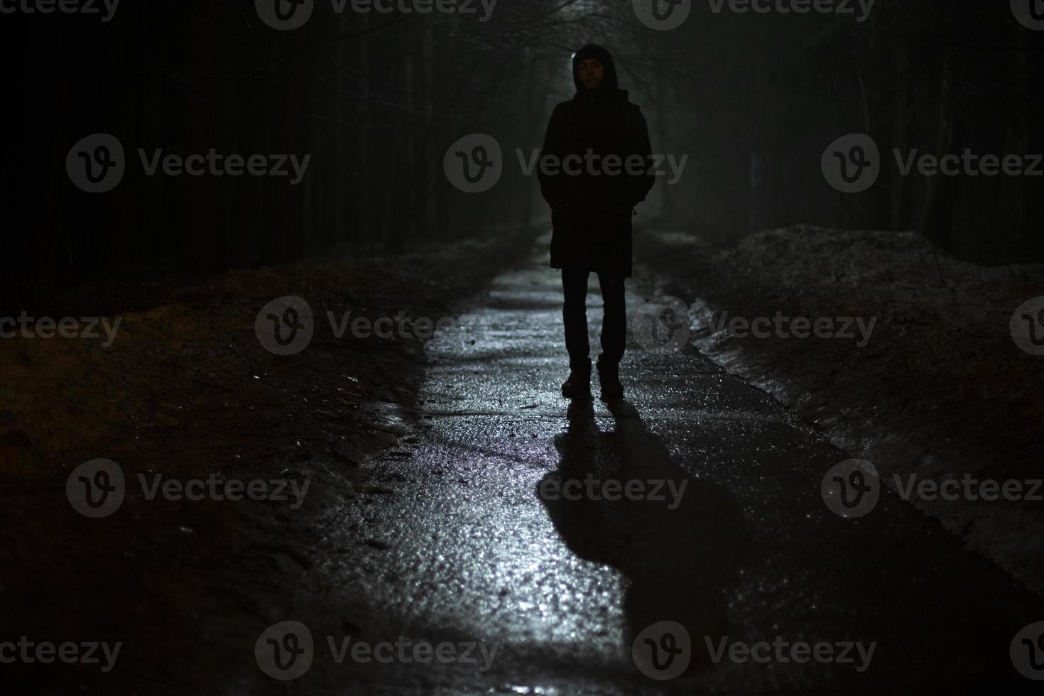 silhuett av man på natt i parkera. man promenader ensam på väg i kväll. foto