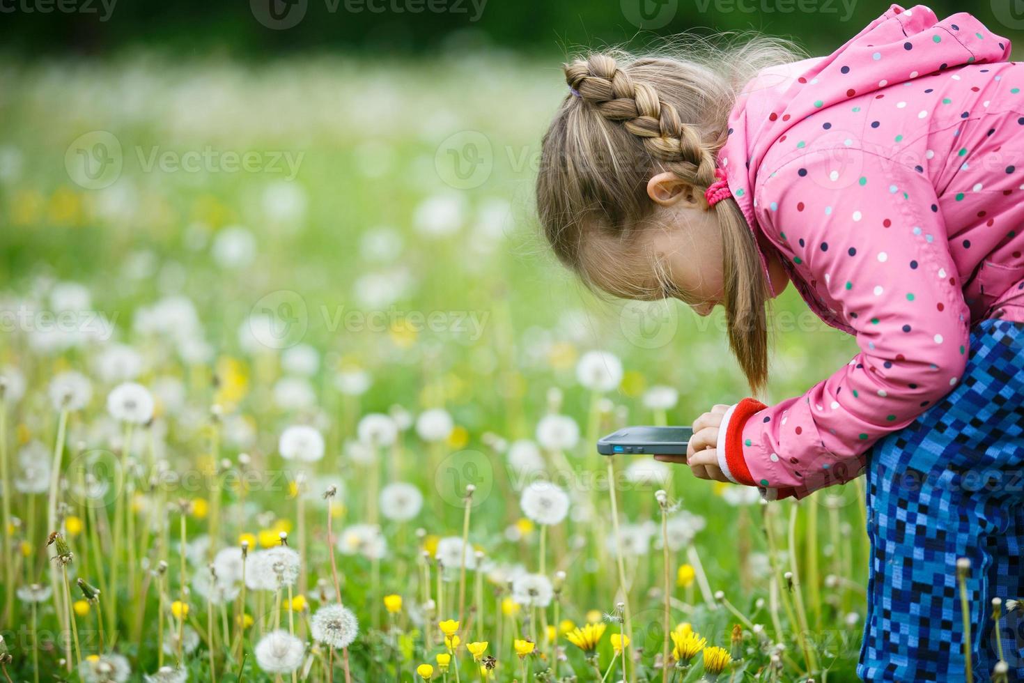 liten flicka som utforskar naturen med sin smarta telefon foto