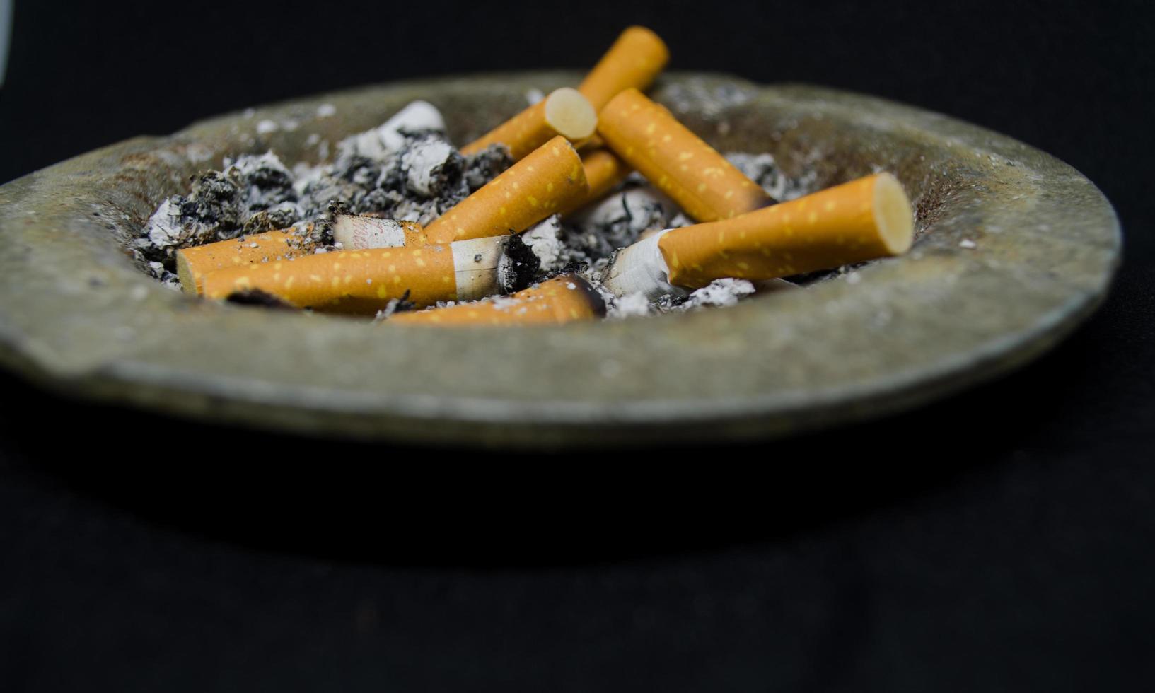 platt se av smutsig cigaretter stånga i de askkopp med svart bakgrund foto
