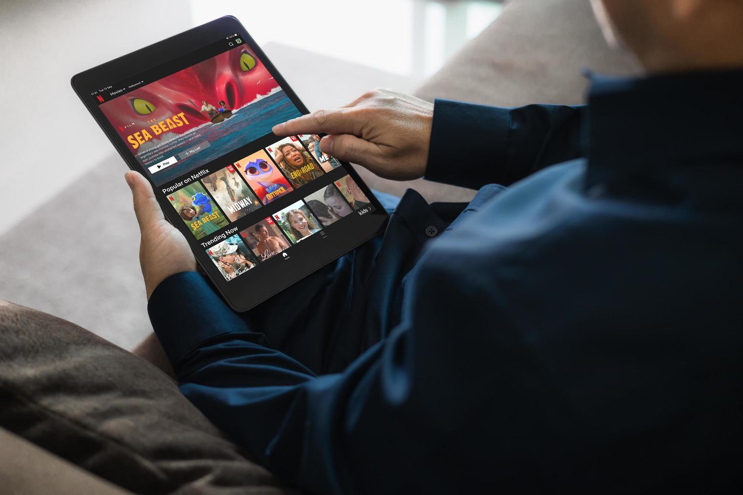 bangkok thailand september 13-2022 manlig använder sig av Netflix Ansökan, strömning bio och TV serier, man innehav ipad på soffa i levande rum på Hem. foto