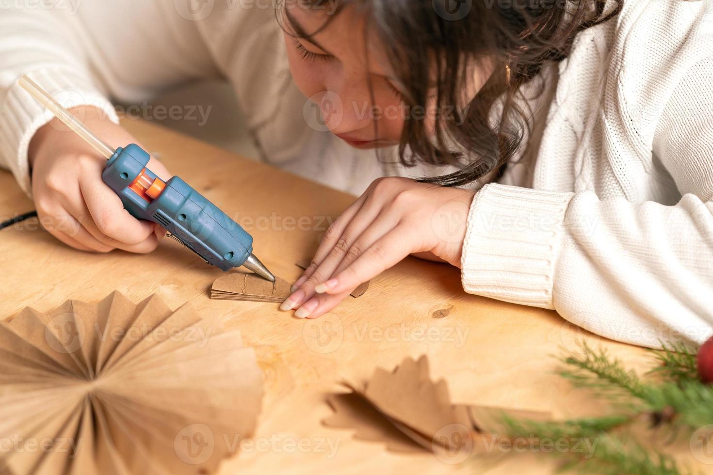 flicka gör jul träd dekorationer ut av papper med henne egen händer. steg 3. steg för steg instruktion foto