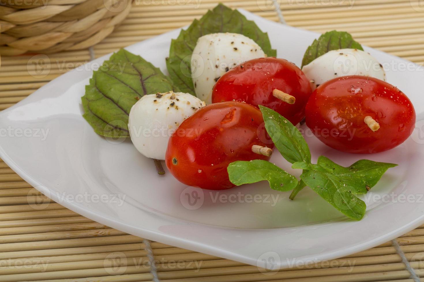 caprese sallad på tallriken och trä bakgrund foto