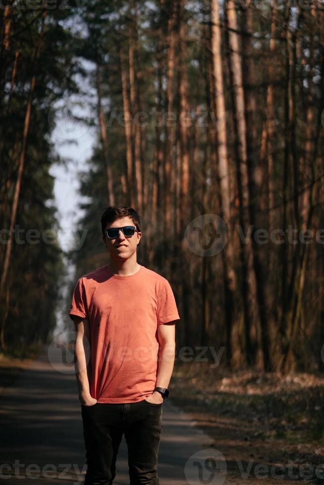 stilig ung man i vit t-shirt och jeans utomhus- i parkera, gående i de parkera foto