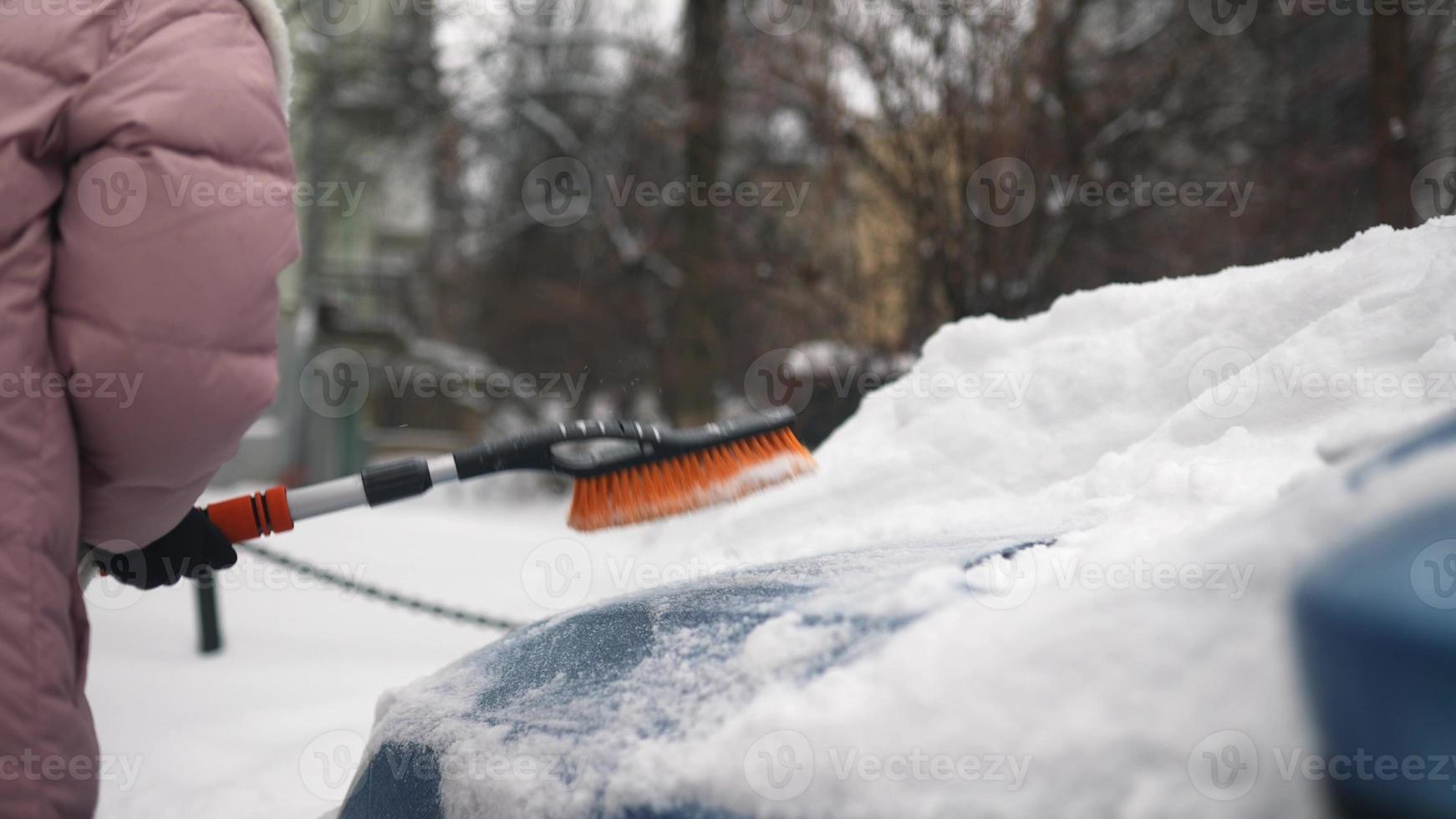 kvinna avlägsnande snö från bil foto