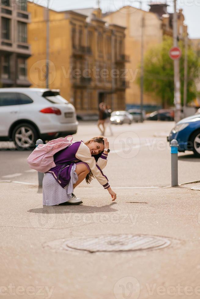 ung skön kvinna Sammanträde i de mitten av de trottoar foto