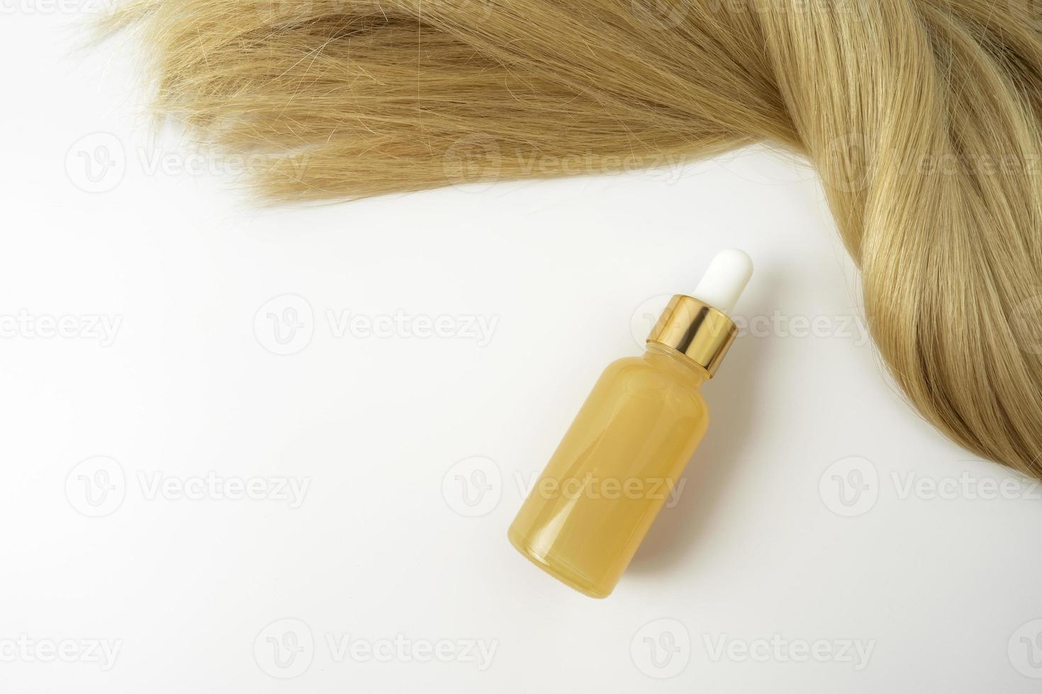 en gul serum för hare vård liggande Nästa till de strå av blond hår foto