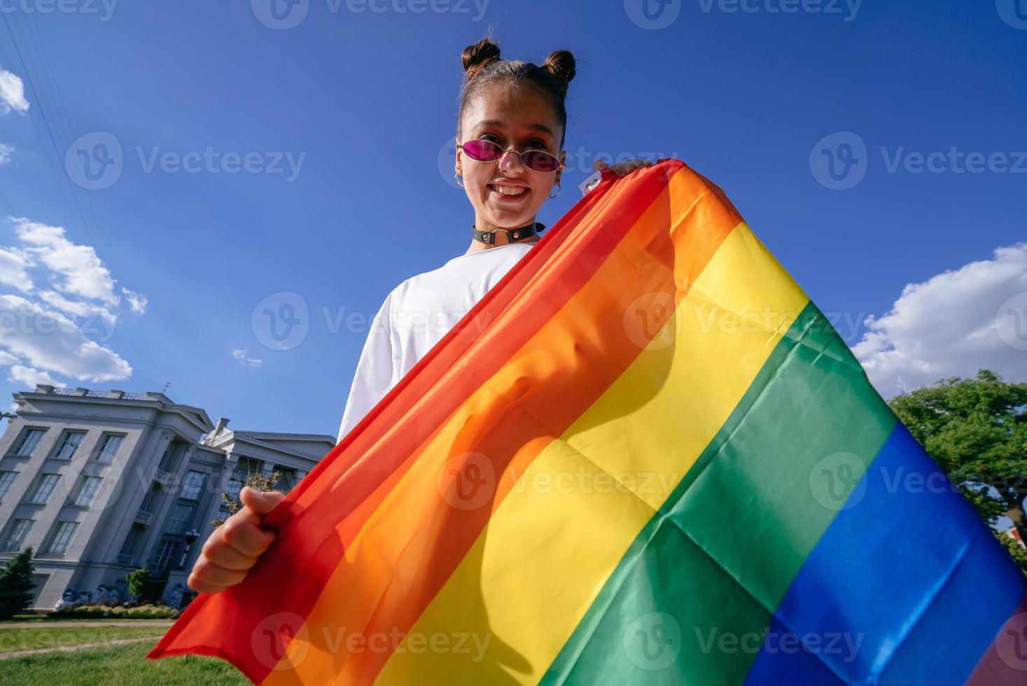 ung kvinna innehav ett HBTQ stolthet flagga i henne händer. foto