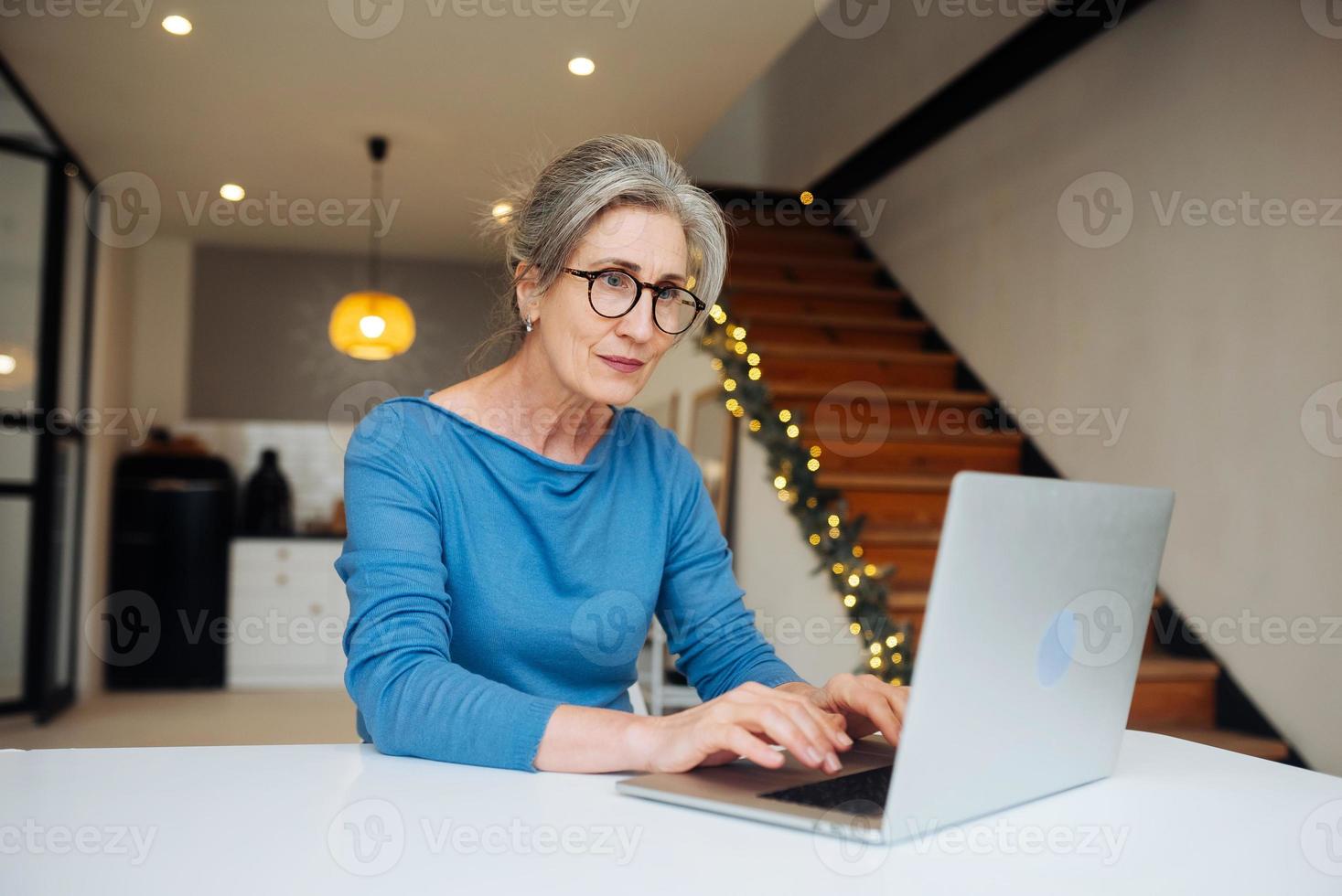 Lycklig mogna mitten åldrig äldre kvinna ser på bärbar dator foto