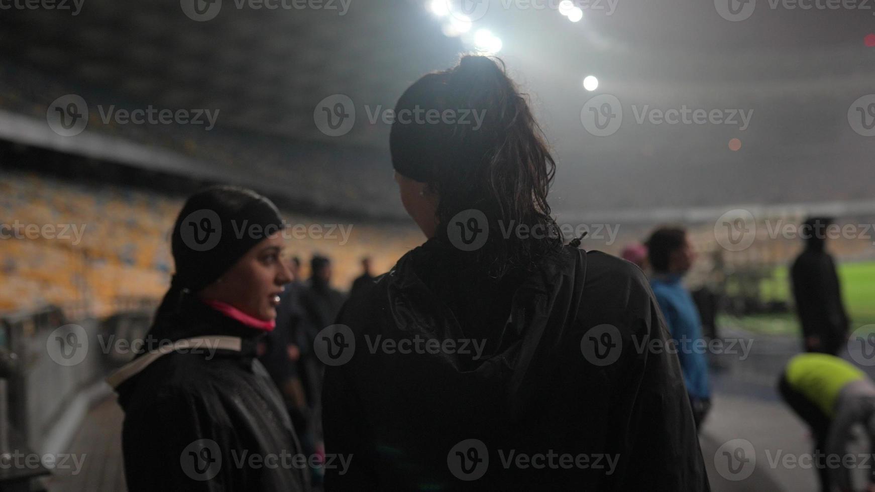 människor gå i för sporter på natt stadion i regnig väder foto