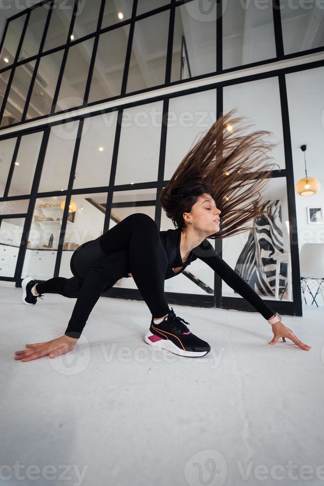 ung kvinna bär svart sporter kostym utövar yoga utgör inomhus. foto