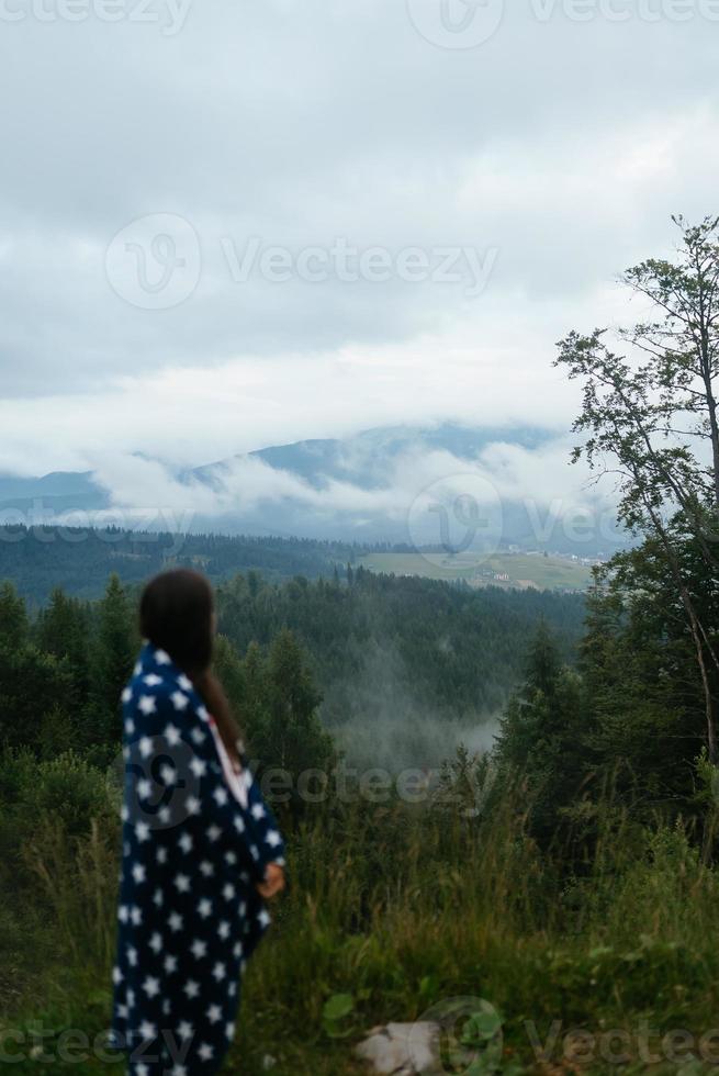kvinna stående på topp av en kulle, mot de bakgrund av en dal foto