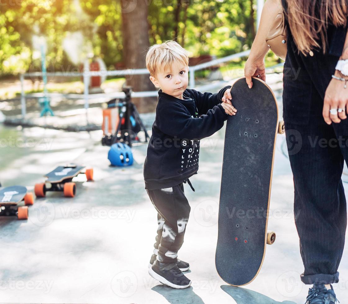 liten pojke bär en stor skateboard utanför foto