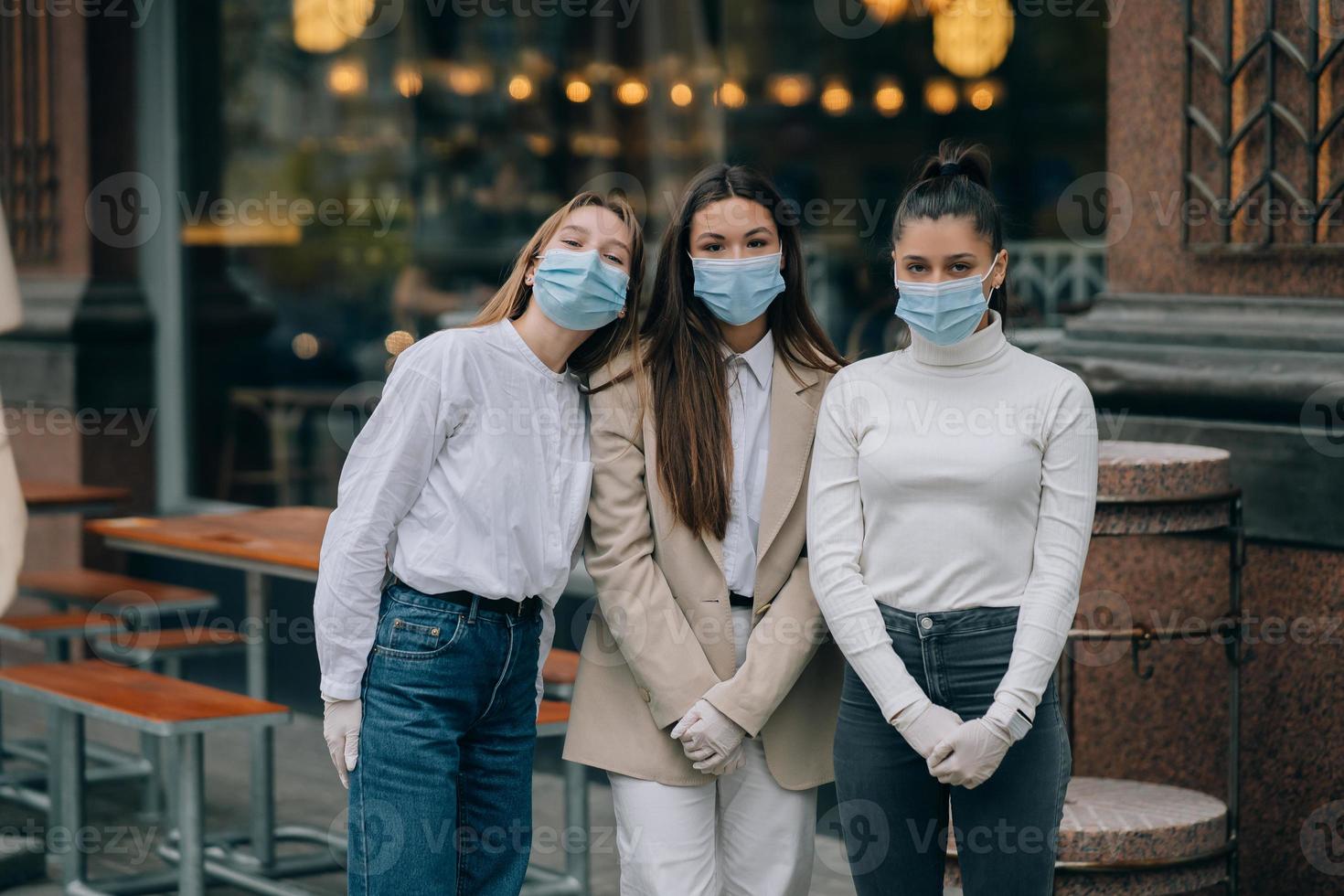 Lycklig vänner ser på de kamera bär skyddande ansikte mask foto