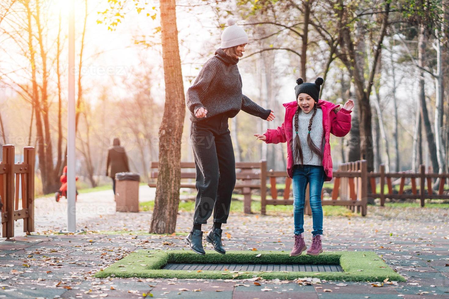 mamma och henne dotter Hoppar tillsammans på trampolin i höst parkera foto