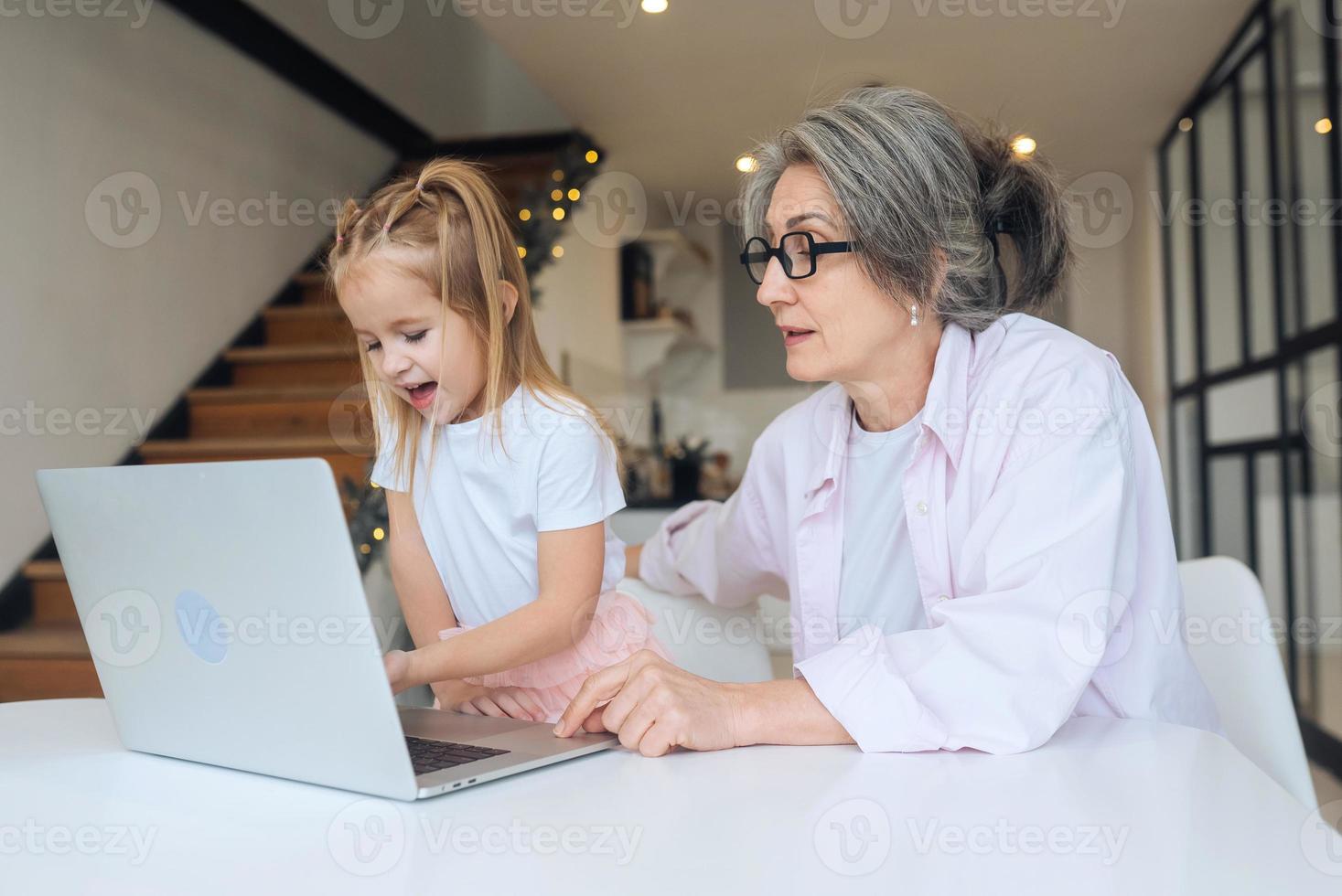barn och mormor ser på de kamera med bärbar dator foto