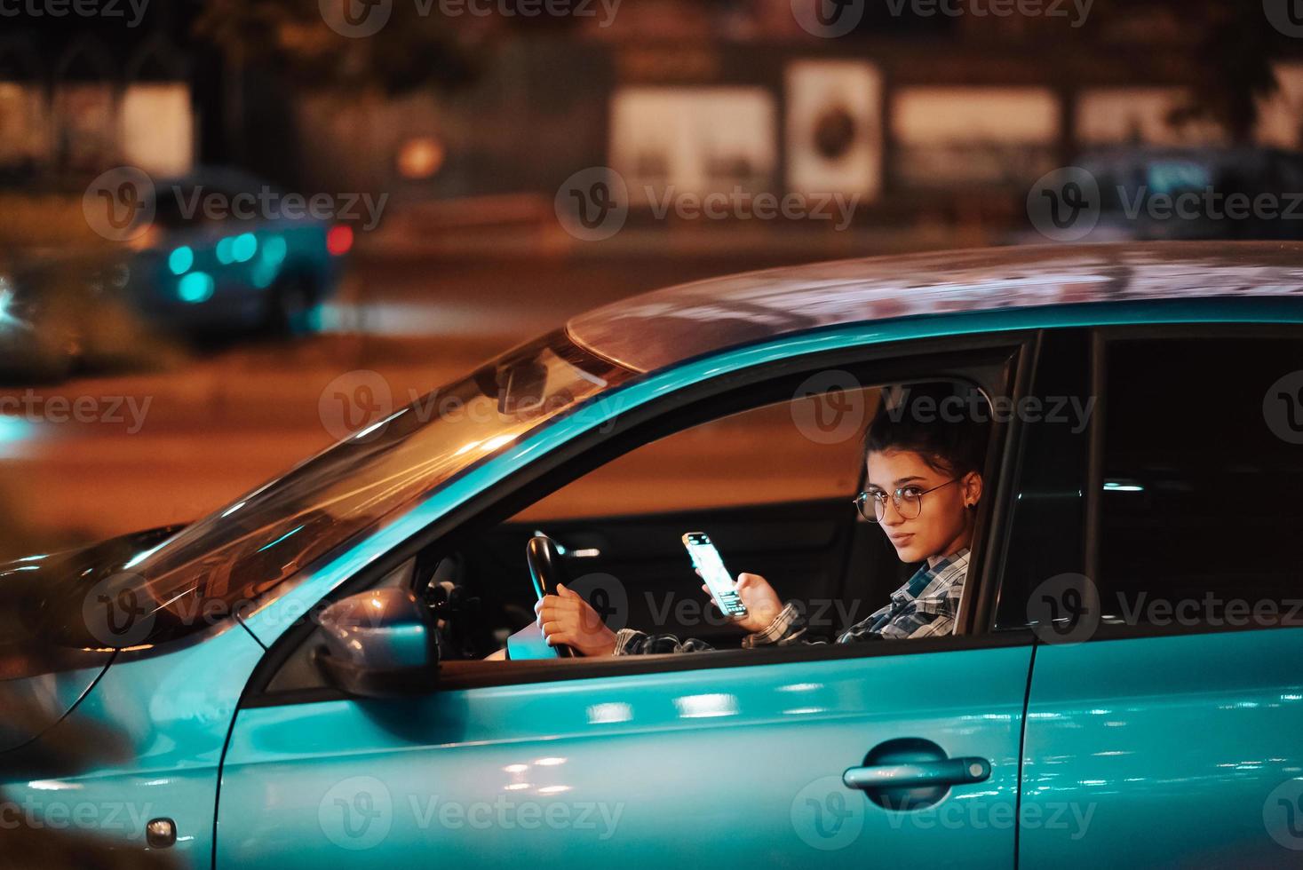 förlorat kvinna förare använder sig av mobil telefon medan körning på natt. foto