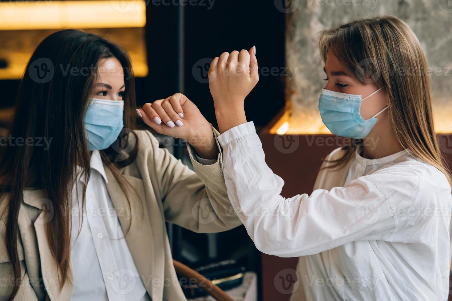 medarbetare i skyddande masker ger hög fem med armbågar. foto