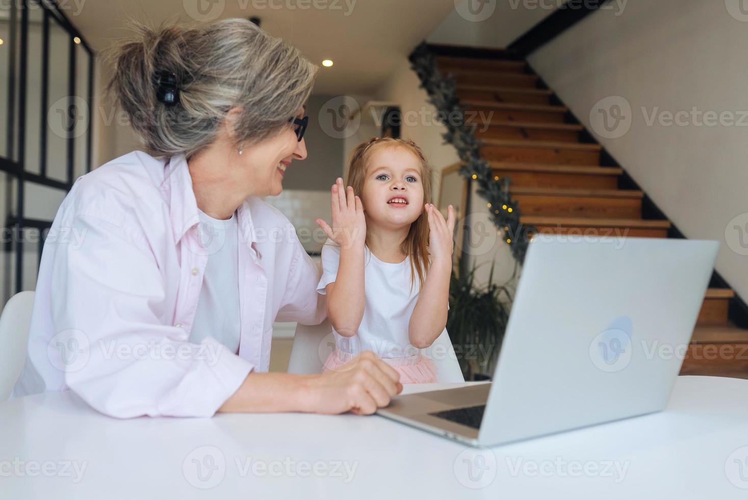 barn och mormor ser på de kamera med bärbar dator foto